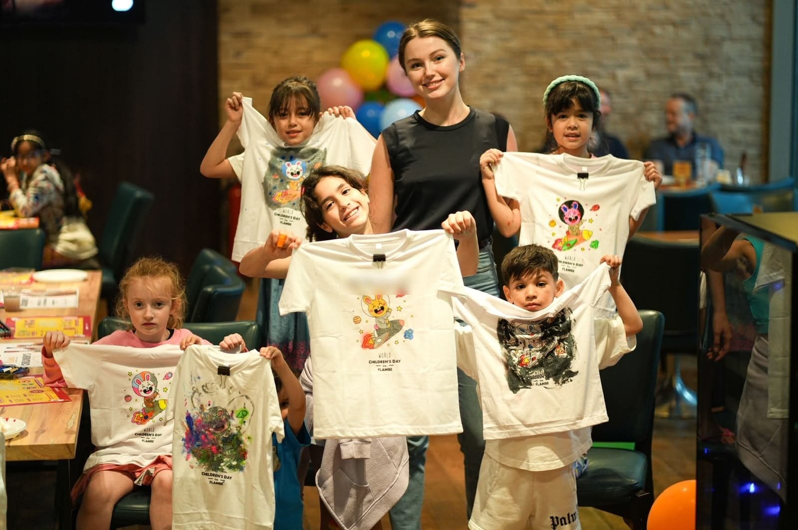 Children holding the T-shirts they painted with Inga Chalaia at the World Children's Day event at Flambé, Dubai