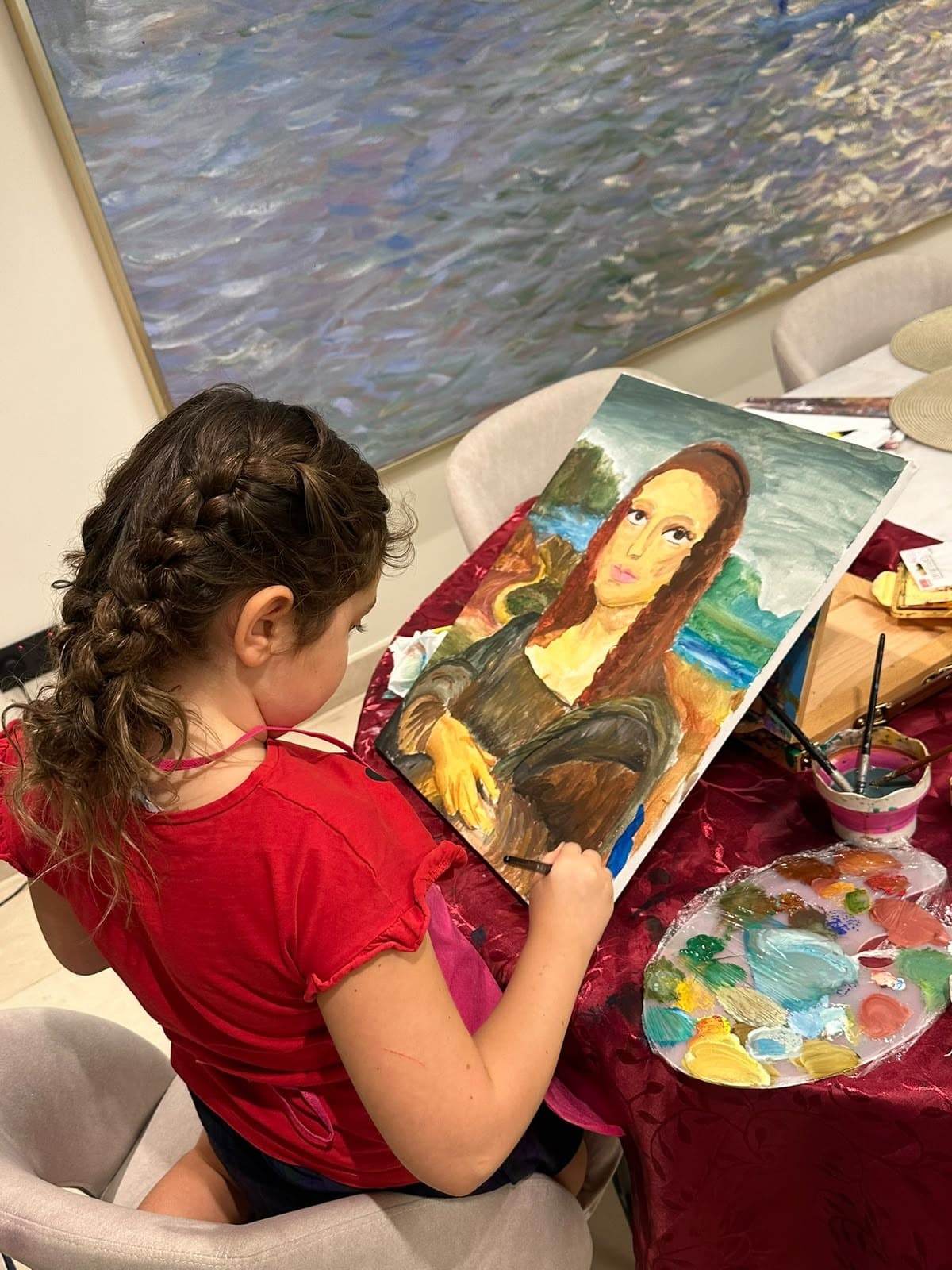 Girl painting her own version of the Mona Lisa at the dining table during a home painting course in Dubai