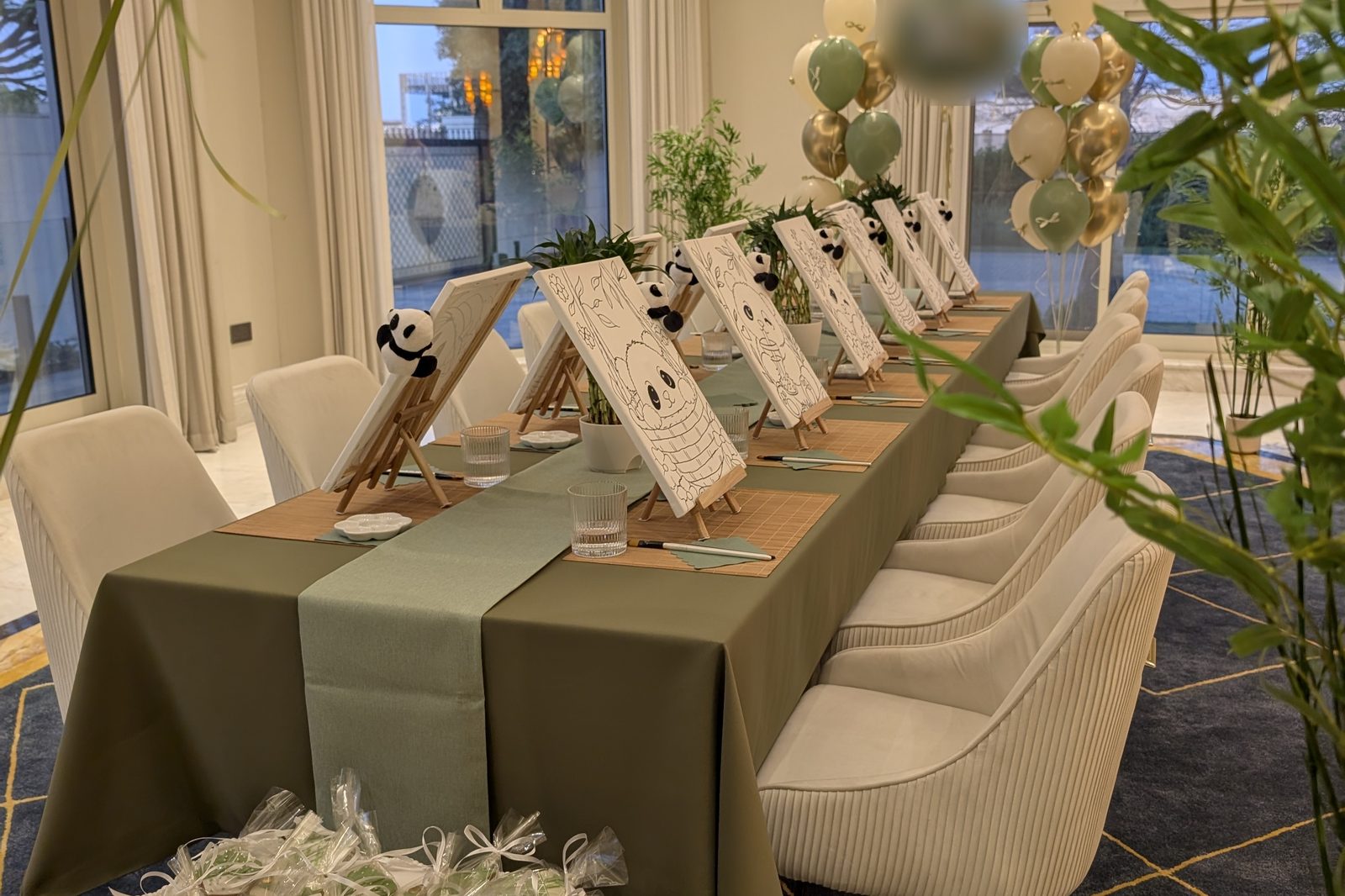 Art themed kids birthday party table in Dubai with panda canvases on easels, sage green tablecloth, bamboo placemats and bamboo plants
