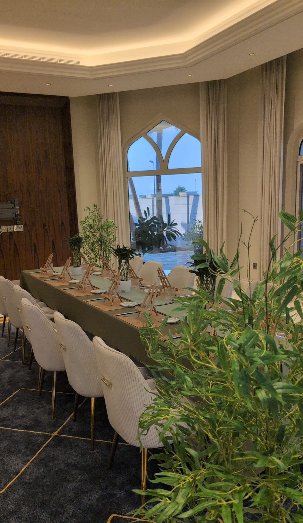 Long kids painting party table set for 12 with tall bamboo plants around it in a living room in Dubai