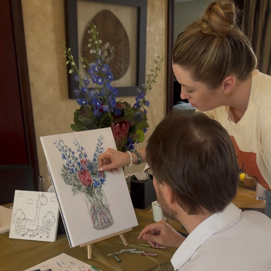 Inga Chalaia guiding an adult student with oil pastels during an in-home painting class in Dubai